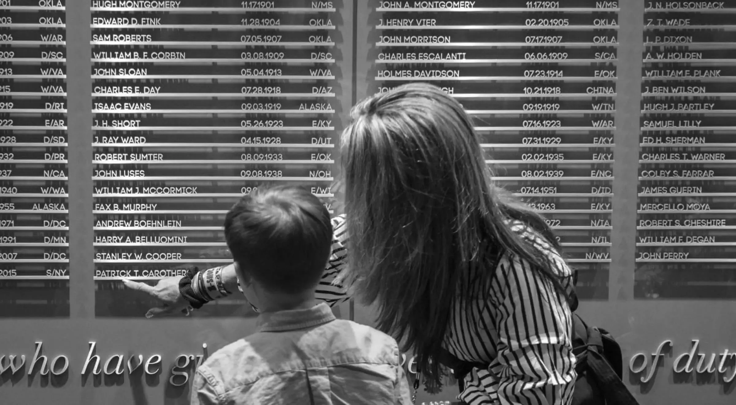 A woman and a child looking at Roll Call of Honor wall